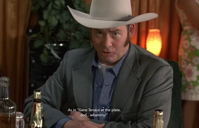 A man wearing a white cowboy hat and gray blazer sits at a table with bottles in front of him, delivering a line referencing baseball player Gene Tenace with a smug or knowing expression. The scene appears to be from a film or TV show with subtitles visible.